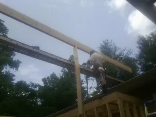 Carpenter setting a ridge beam over a new addition frame — Ice Dam Removal by Roofing Brothers in Brookline