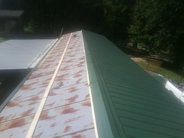 Old rusted panels beside newly installed green metal roofing — Wind Damage Roof Repair by Roofing Brothers in Brookline