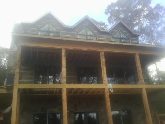 Dormers and porch framing on a large log home under construction — Roof Coating work by our crew in Brookline